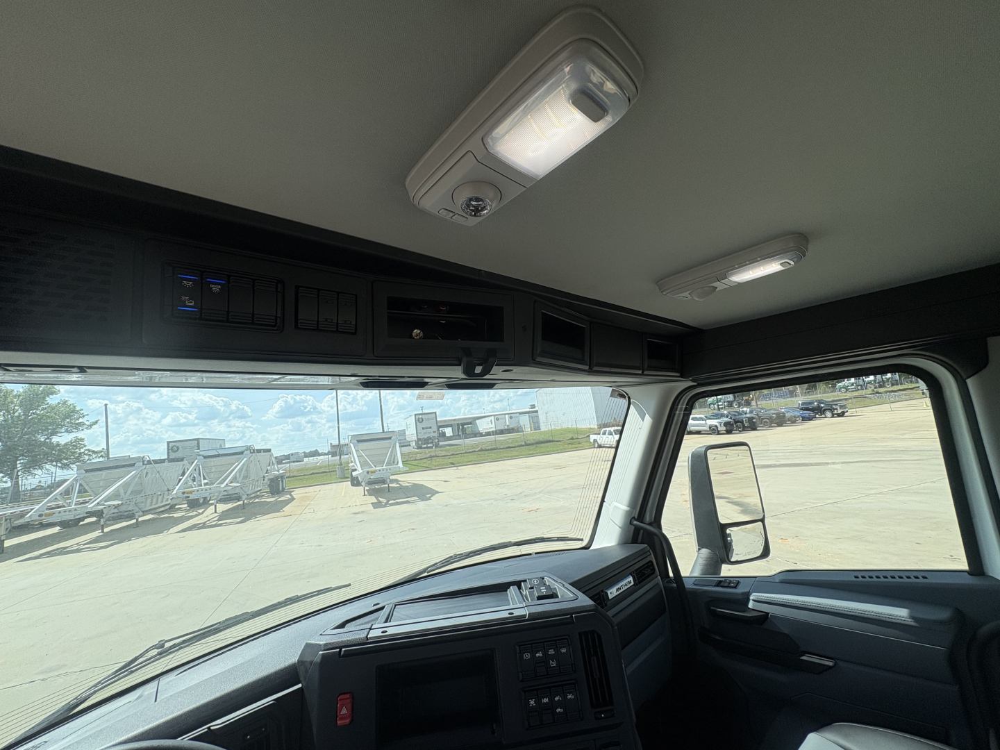 Cab interior of a 2027 Mack AN64T truck showing overhead console, interior lights, and dash area viewed from the driver seat.