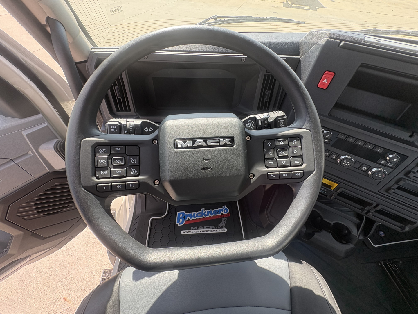 Mack AN64T truck steering wheel and dashboard view in cab showing Mack logo and control buttons on steering wheel