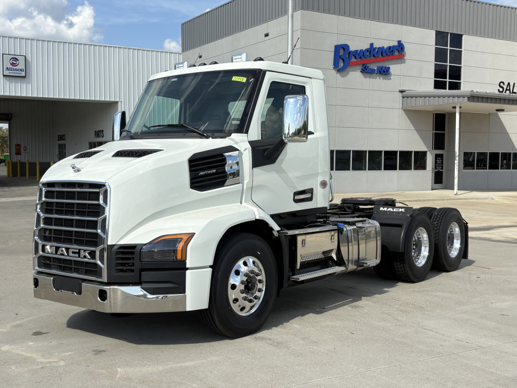 Mack AN64T conventional daycab truck in white parked outside dealership with front grille and chrome mirrors.