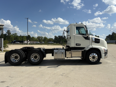 Side view of a white 2027 Mack AN64T conventional daycab truck chassis with dual rear axles, fuel tanks, and mounted equipment.