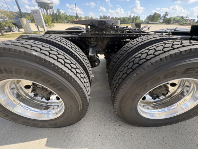 Dual rear truck wheels and chassis framing of a 2027 Mack AN64T daycab with large tires and chrome wheels, view of drive axle center.