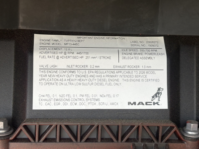 Mack engine information label on a truck engine bay: engine family, series MP?4, horsepower and RPM ranges, valve lash specs, exhaust rocker, intake rocker, fuel rate, and def warning. Mack logo visible.