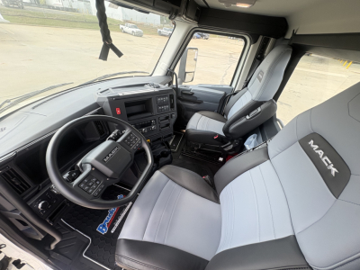 Interior of a new 2027 Mack AN64T daycab highlights the steering wheel, dashboard, driver seat with Mack branding, and passenger seat.