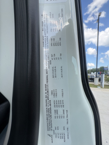 Vehicle information label inside a Mack AN64T cab door. Contains VIN, stock number, category, type, and condition details. Visible text includes VIN 1M1A24GY7VM102526, Stock 72148, Category Conventional Daycab, Type Trucks, New/Used New.