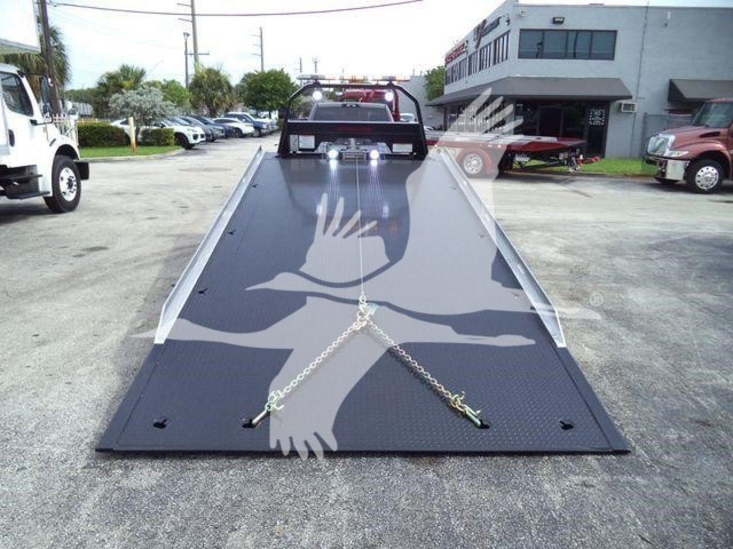 Ram 5500 rollback tow truck flatbed in roadway with safety chains and towing hooks visible