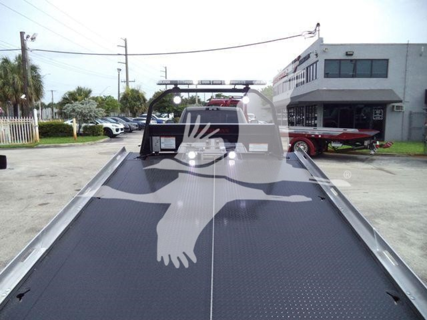 Ram 5500 rollback truck bed with metal diamond-plate surface and hitch area, rear view showing cab and equipment in background.