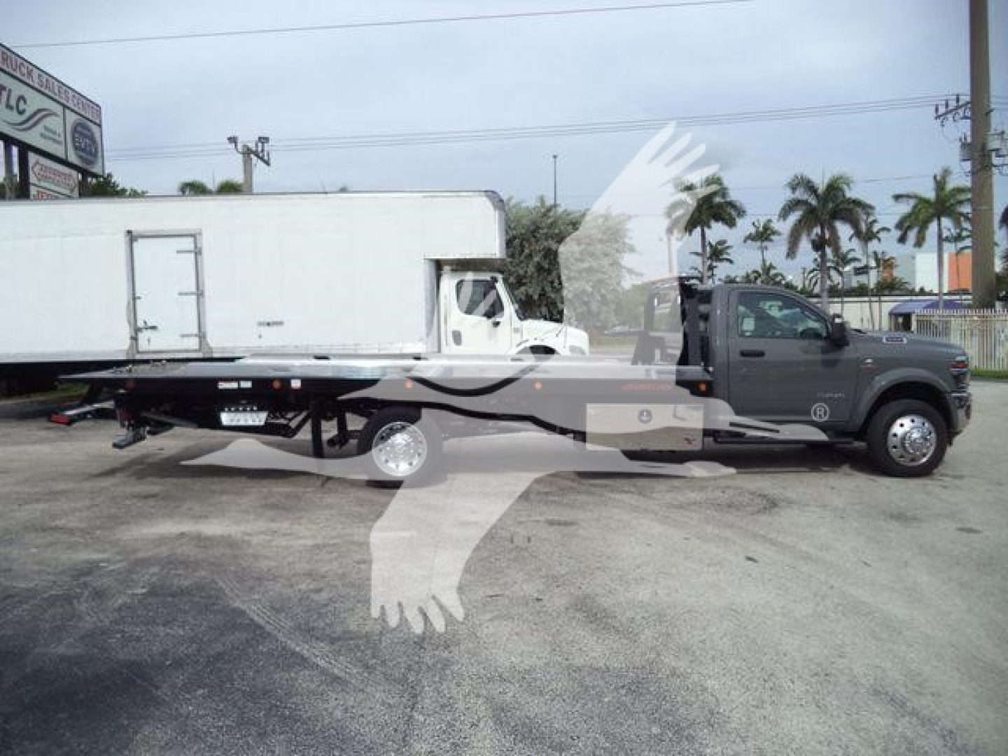 2026 Ram 5500 Big Horn truck with flatbed rollback body and attached white cargo trailer in a dealership lot.