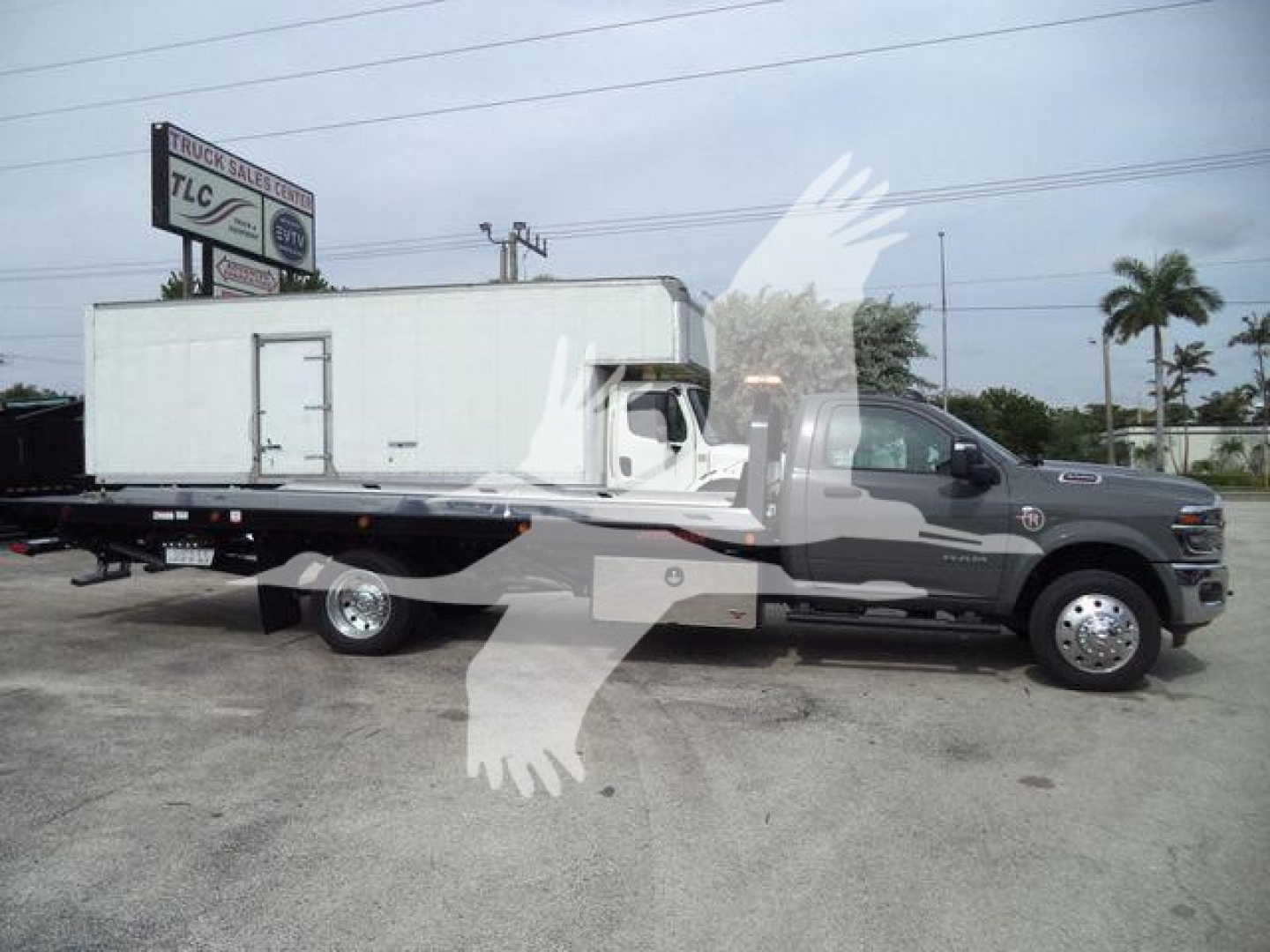 Truck bed with large white utility box on a Ram 5500 chassis cab, side view showing extended rollback bed and storage compartments.