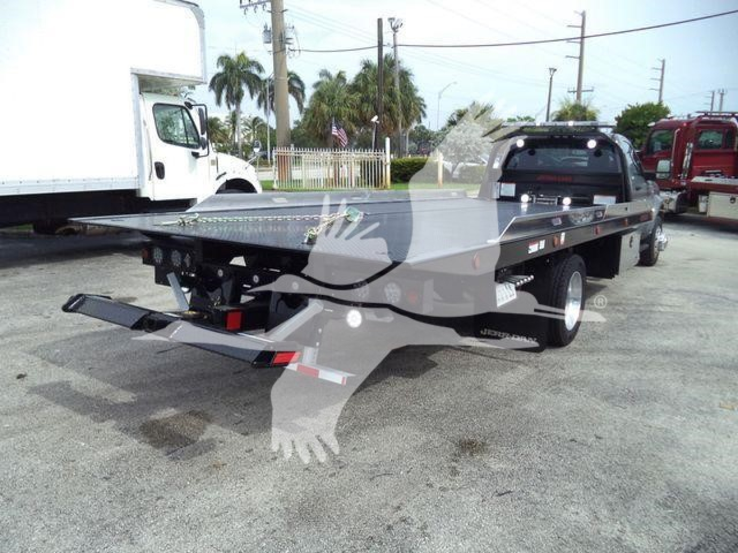 Ram 5500 rollback tow truck flatbed shown from rear-right view with loading ramps and hitch.