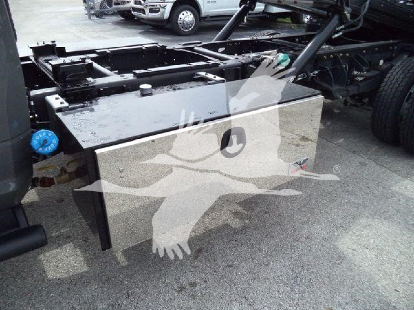 Truck chassis with large rectangular aluminum toolbox mounted beside cab showing top and side views.