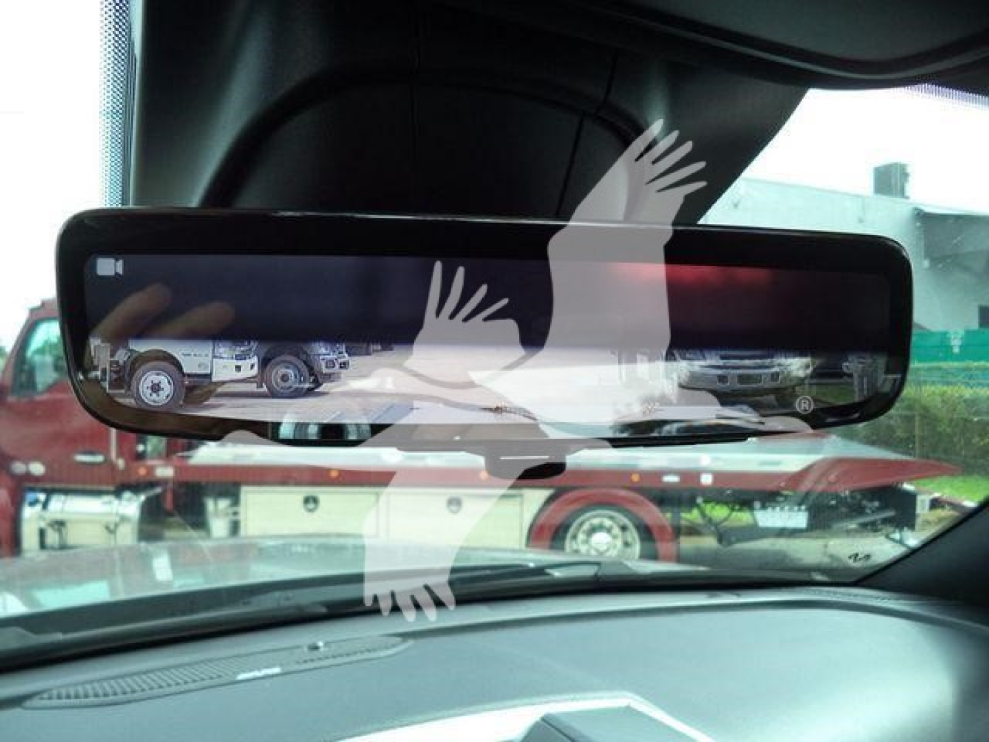 Rearview mirror display shows trucks and a rollback equipment; vehicles visible through windshield. Text on screen includes VIN and stock number in listing context.