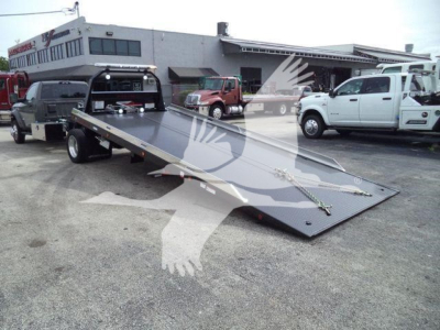 Ram 5500 rollback tow truck flatbed with white cab and black flatbed, dealership lot in background, stock photo watermark across center.