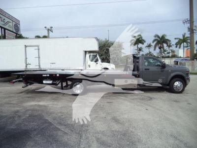 2026 Ram 5500 Big Horn truck with flatbed rollback body and attached white cargo trailer in a dealership lot.