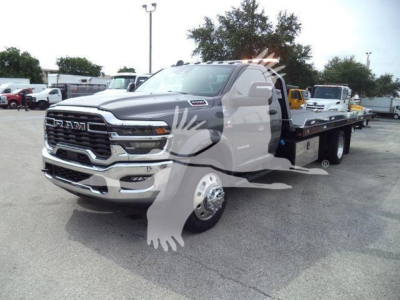 Ram 5500 rollback tow truck in metallic gray with extended flatbed, front grille RAM logo and dual rear wheels, dealership lot background.