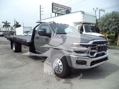 Ram 5500 rollback tow truck in a dealership lot, front three-quarter view with extended wheelbase, RAM badge on grille, and flatbed in rear.