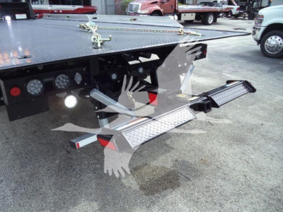 Ram 5500 rollback chassis with diamond plate flatbed and fold-out wheel ramps; visible toolbox LEDs and rear step, license-plate area, and sturdy hitch.