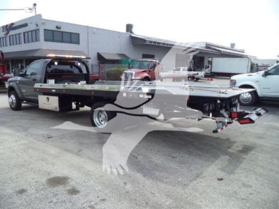 Ram 5500 rollback tow truck with flatbed viewed from rear/side showing long flatbed and towing equipment.