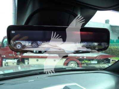 Rearview mirror display shows trucks and a rollback equipment; vehicles visible through windshield. Text on screen includes VIN and stock number in listing context.