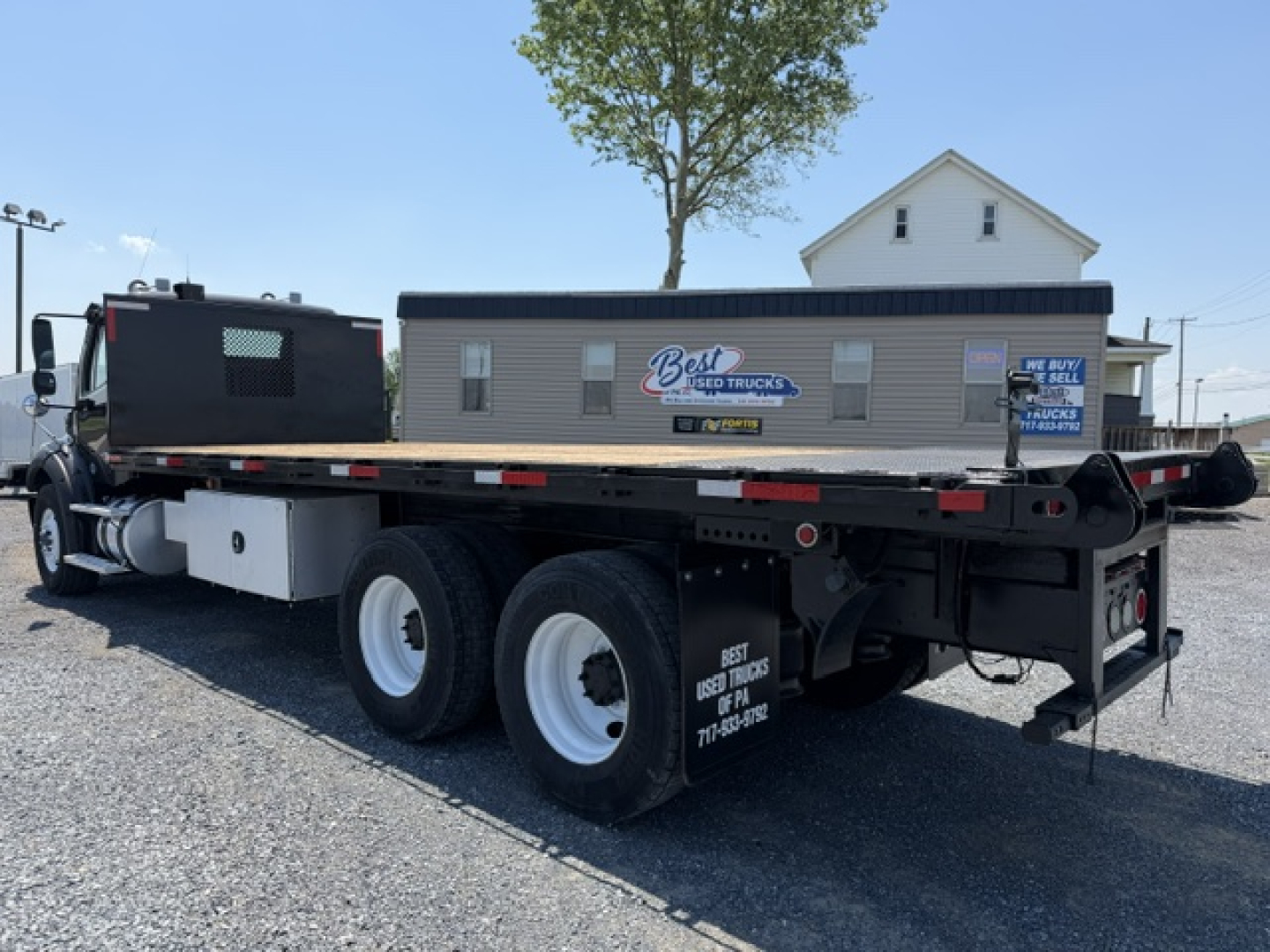 Flatbed truck tractor trailer rear view showing dual rear axles and flatbed with equipment trailer hitch, Freightliner M2-112 2016.