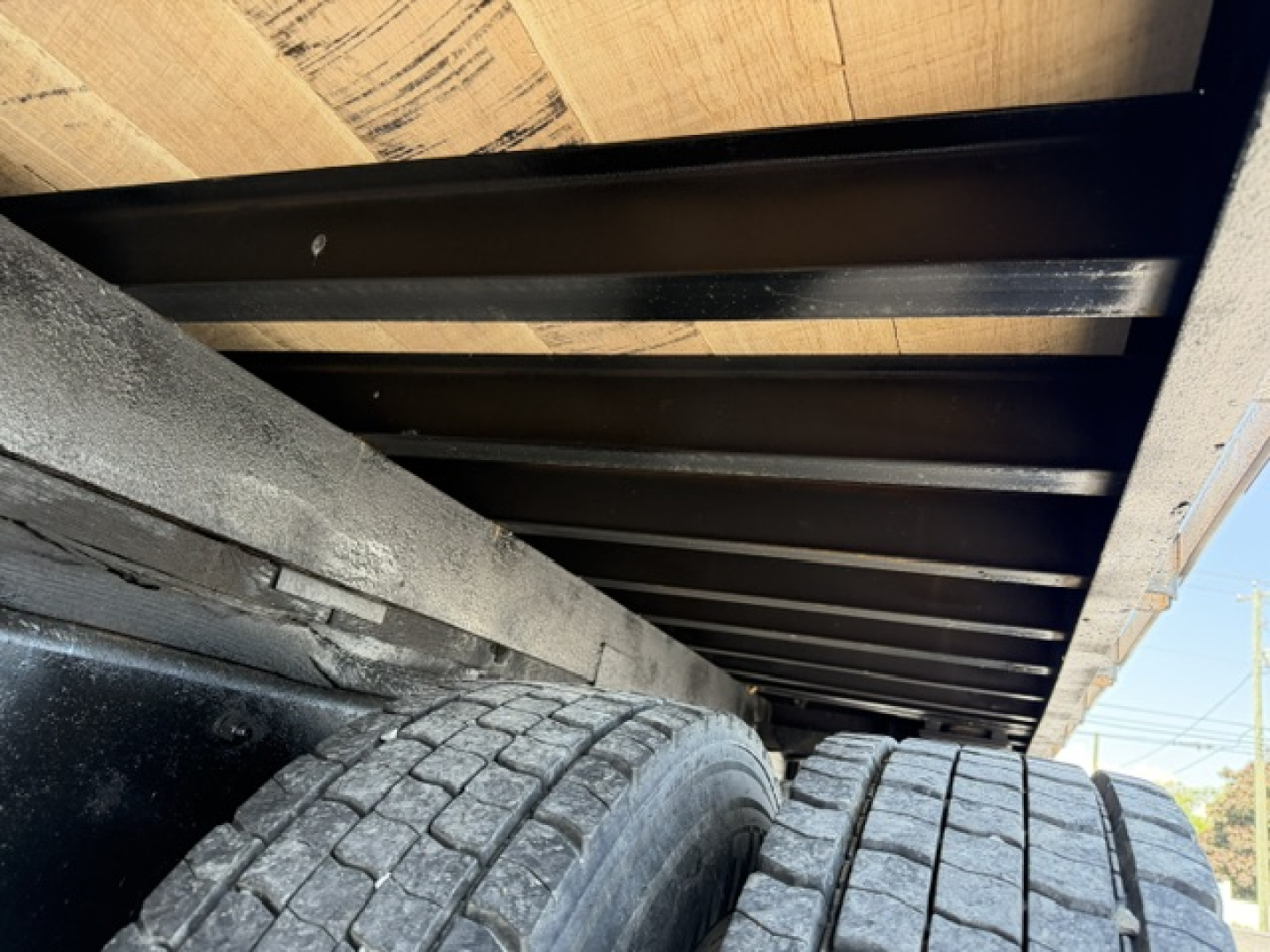 Flatbed truck underside showing dual rear tires and undercarriage framework.