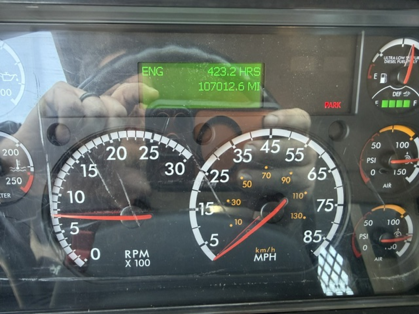 Freightliner M2-112 gauge cluster view with digital ENG hours and miles display showing 423.2 HRS and 107012.6 MI; speedometer and RPM gauges visible.