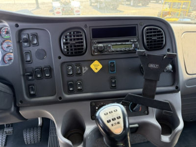 Freightliner M2-112 cab interior showing center dashboard with storage/air vents, radio, switches, steering column, and gear shifter.