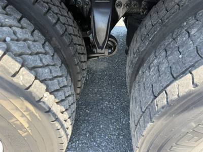 Truck rear axle dual tires and suspension components visible between wheels in a Freightliner M2-112, showing dual rear tires and undercarriage details.