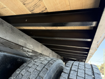Flatbed truck underside showing dual rear tires and undercarriage framework.