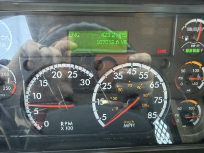 Freightliner M2-112 gauge cluster view with digital ENG hours and miles display showing 423.2 HRS and 107012.6 MI; speedometer and RPM gauges visible.