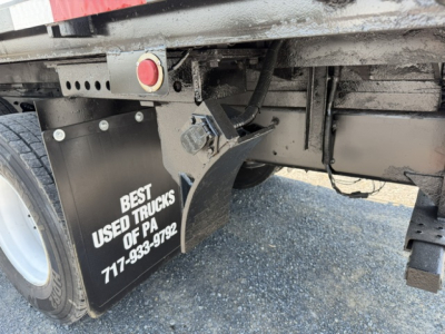 Freightliner M2-112 rear undercarriage showing mudflap with 'BEST USED TRUCKS OF PA 717-...' and rear tire; wiring and frame components visible.