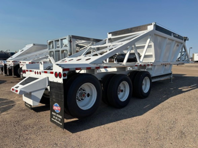 Dump trailer showing three axles and white steel framing under clear sky; label plate and wheels visible; CPS Versa Va trailer in new condition.