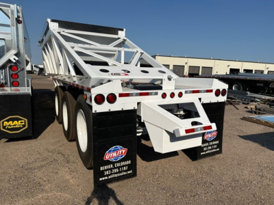 Dump trailer showing white Versa Versa Va with dual rear ramps and tri-axle configuration. Visible stickers include US flag license plate and utility city Denver Colorado contact mudflap details.