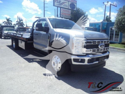 Front-left view of a Ford F-600 XL T truck with a flatbed rollback bed, chrome grille, and large side mirrors. VIN plate and dealership sign in background.