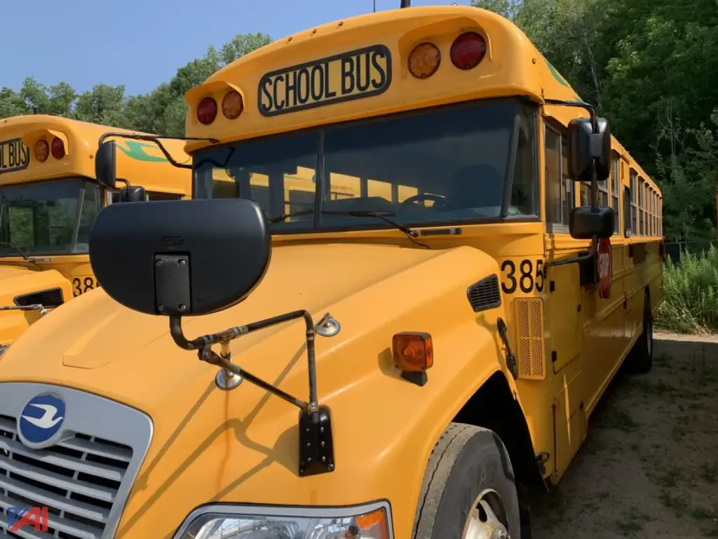 School bus in view showing front and side, yellow body, 'SCHOOL BUS' sign, black hood mirror, wheel, and bus number 385.