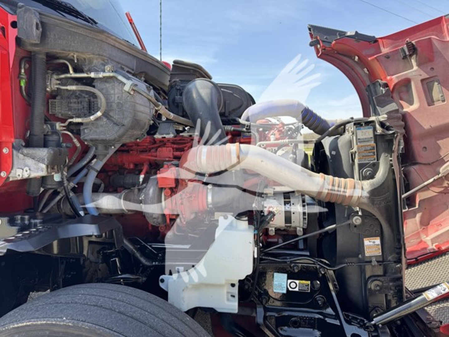 Kenworth T680 engine bay view showing fuel lines, air intake, hoses, and coolant reservoir in front engine area.