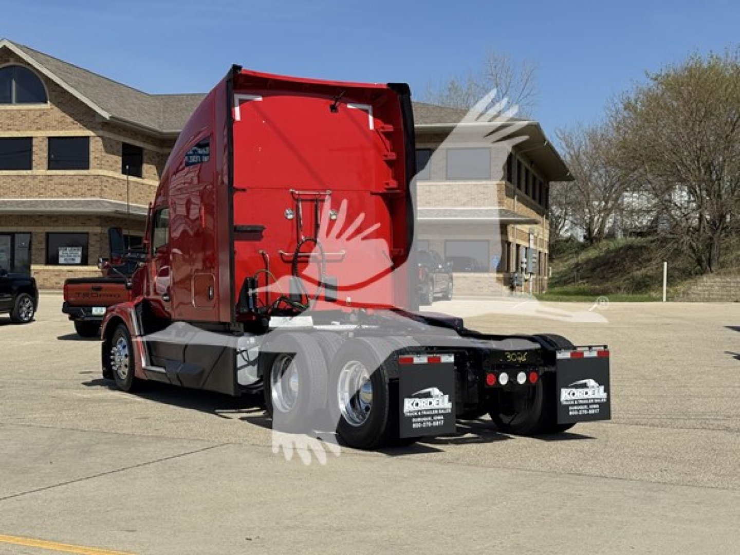 Kenworth T680 tractor rear/side view showing fifth wheel and dual rear axles, red cab, black chassis, dealership stickers on mud flaps.