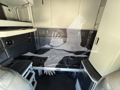 Kenworth T680 truck sleeper cab interior view showing storage compartments and raised decking with exposed framing.