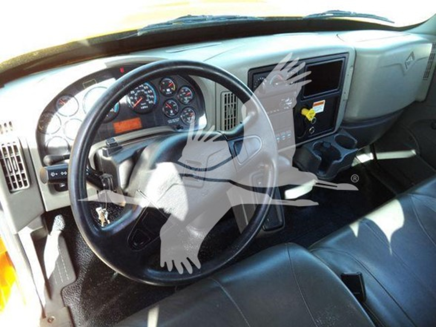 Truck cab interior of 2019 International Durastar 4300 showing steering wheel dashboard gauges and driver seat from the left side.