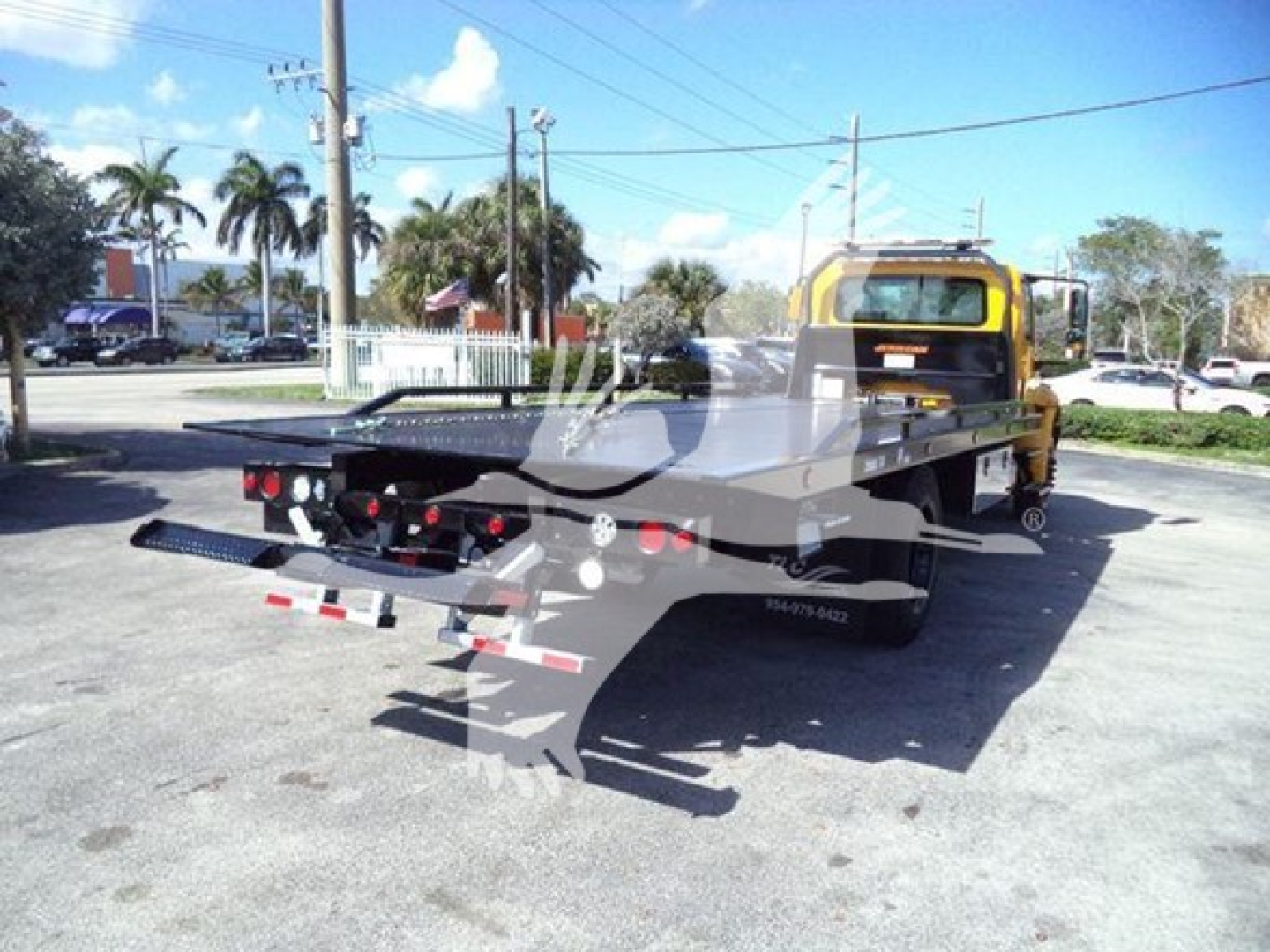 2019 International Durastar 4300 rollback tow truck with a flatbed, rear view showing rear lights and loading ramps, VIN plate area not legible.
