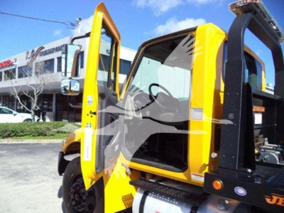 2019 International Durastar 4300 rollback truck with open driver door, yellow cab, and black equipment frame visible.
