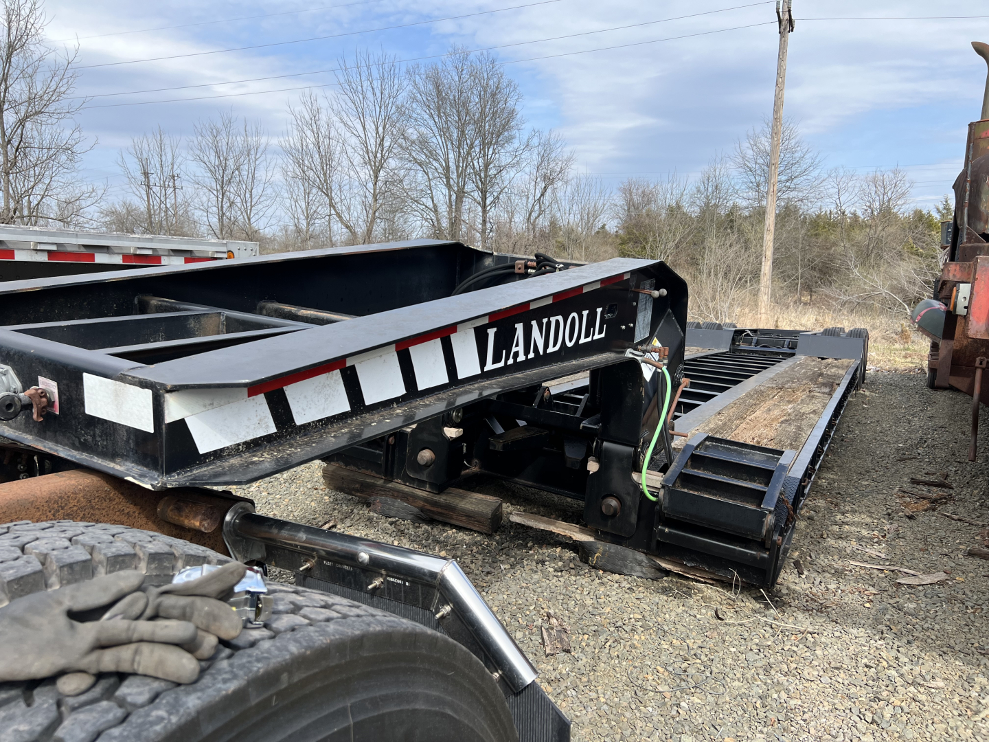 Landoll 326A lowboy trailer frame showing 'LANDOLL' logo and black steel beams with wheel chassis and tracked components
