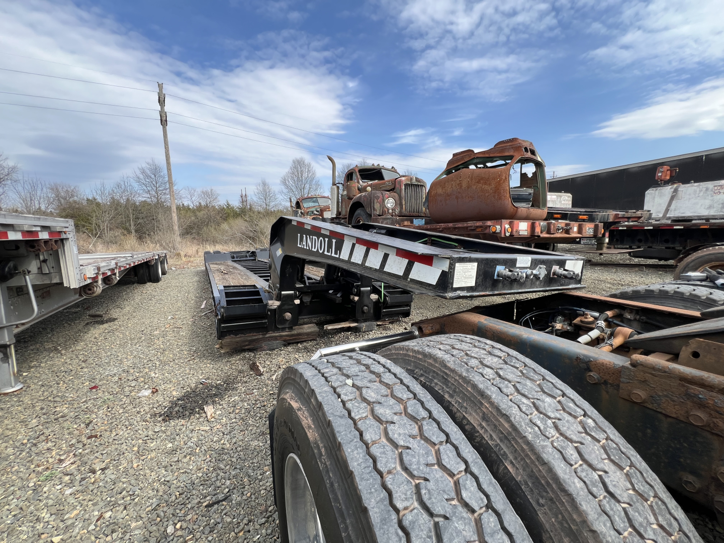 Lowboy trailer showing Landoll 326A branding and dual rear wheels with chrome wear plates and reflective tape.