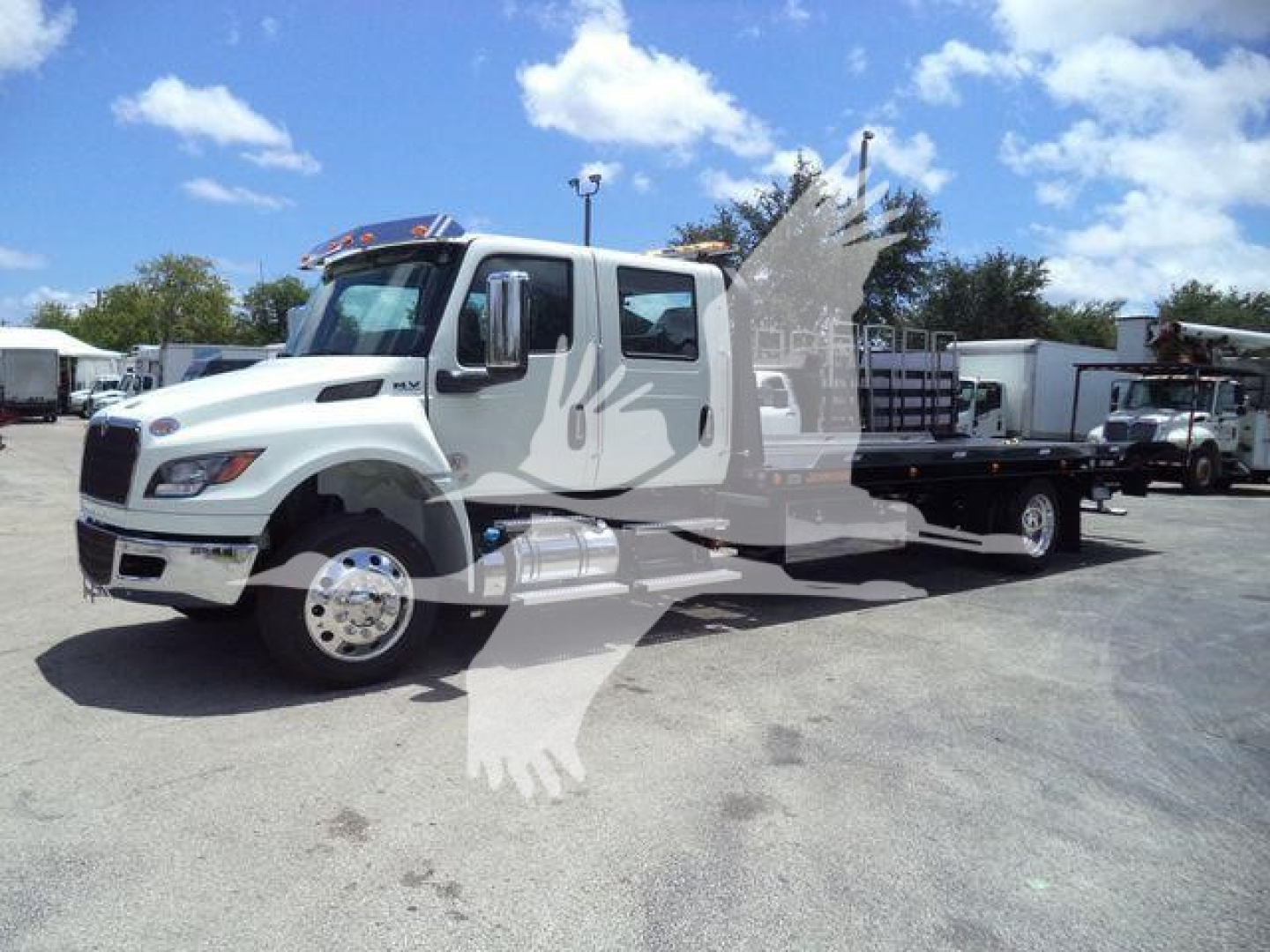 Truck cab and flatbed rollback tow truck in a dealership lot with stock number MVCREW22SRRD6T.