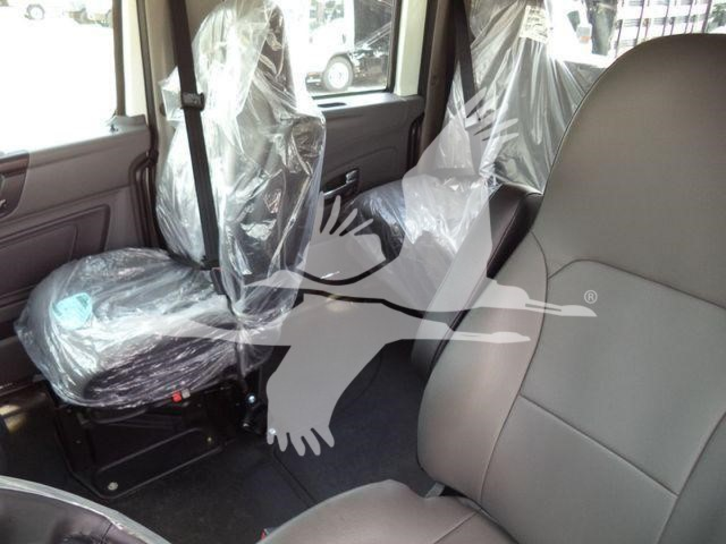 Interior of a 2026 International MV truck showing front and rear seats with plastic protective covers.