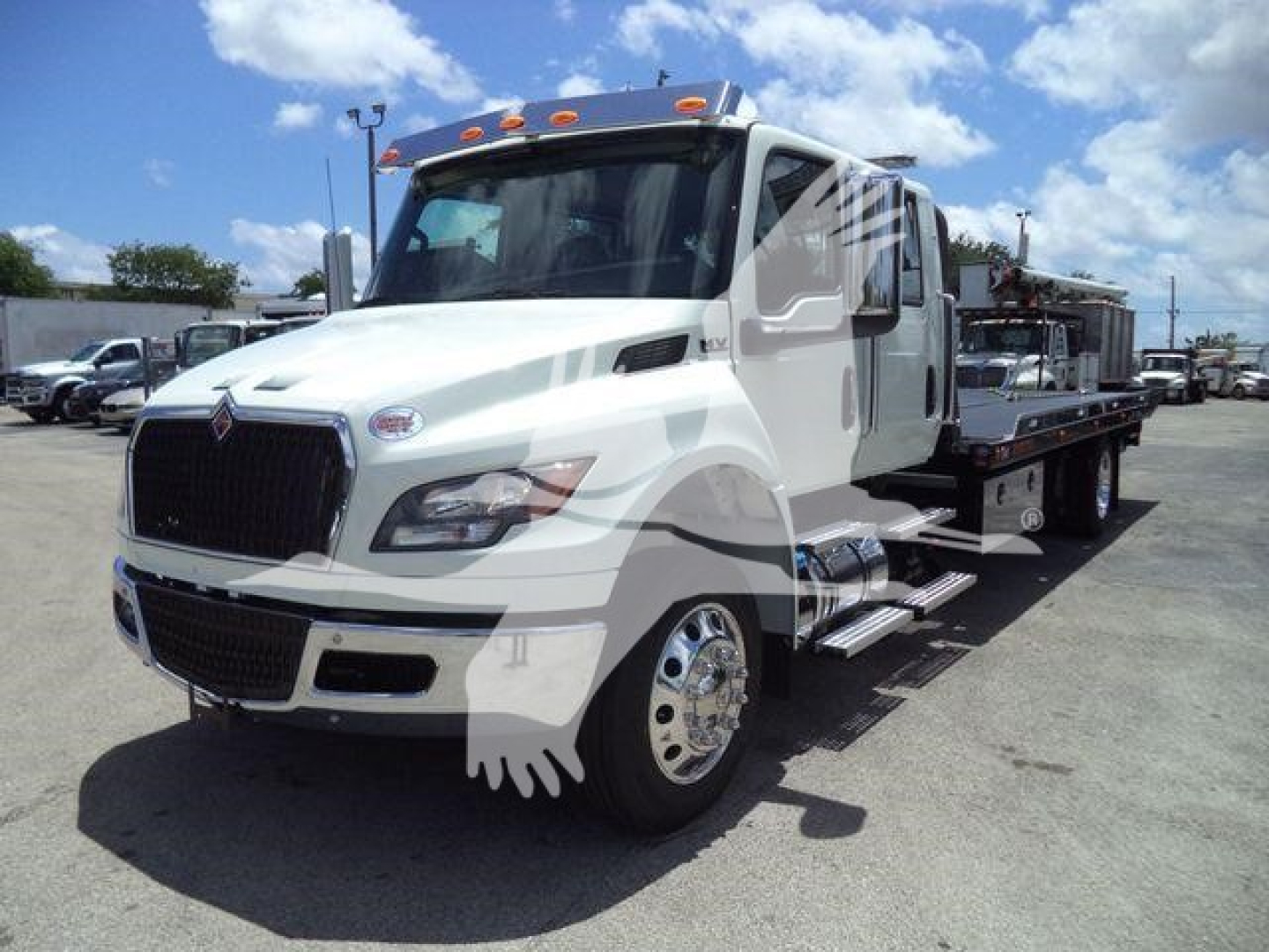 International MV series tow truck/rollback truck in white, front-left view, with hydraulic flatbed and chrome wheel rims.
