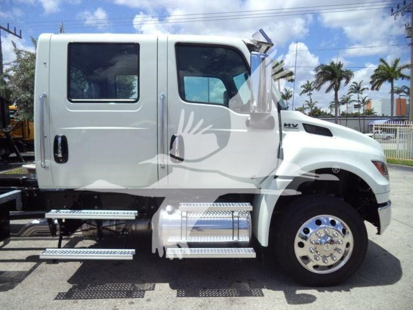 International MV truck cab side view with chrome steps and tanker chassis, white finish.
