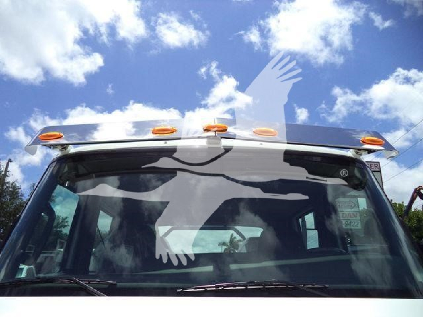 Truck cab front windshield of a 2026 International MV rollback truck showing roof lights and front view.