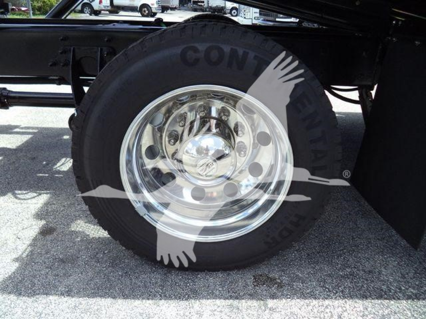 Wheel and tire on a new International MV rollback truck showing a polished chrome rim and Conti tire, partial undercarriage visible.