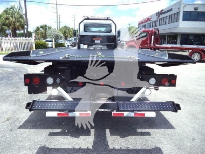 Rear view of a black rollback bed on a 2026 International MV truck with hydraulic flat bed and taillights visible.
