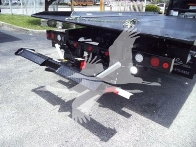 Truck rollback bed with rear step and taillights visible under the platform; black metal steps extend outward from the back.